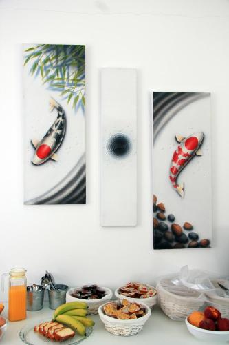 three pictures of fish on a wall with bowls of food at Ifestos Villa in Fira