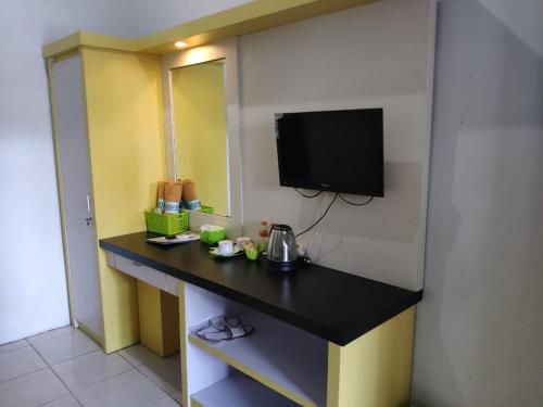 Habitación con escritorio y TV en la pared. en Hotel Boegenviel Syariah, en Lamongan