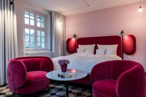 a bedroom with a bed and two chairs and a table at Mintrops Stadt Hotel Margarethenhöhe in Essen
