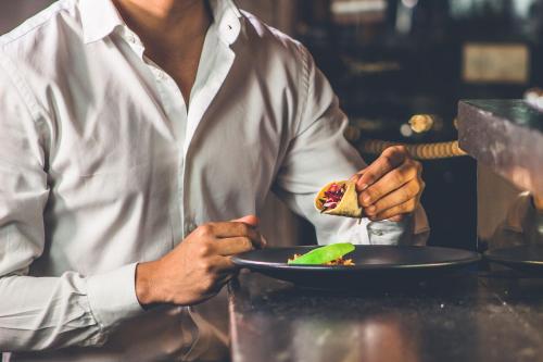 a man is holding a plate with a sandwich at Central Hotel Boutique in Chihuahua