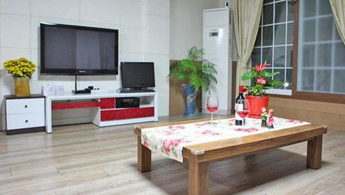 a living room with a coffee table and a flat screen tv at Tongyeong Bada Sarang Pension in Tongyeong