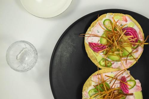 two sandwiches on a black plate next to a glass of water at Central Hotel Boutique in Chihuahua