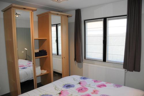 - une chambre avec un lit et un miroir dans l'établissement Villa KARIN, à Oostduinkerke