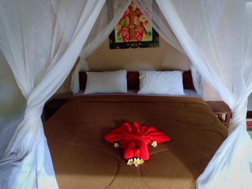 a bed with a red stuffed animal sitting on it at Menjangan View in Banyuwedang