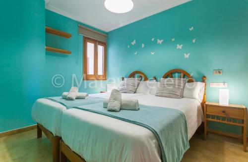 a blue bedroom with two beds and a window at Orellana in Can Picafort