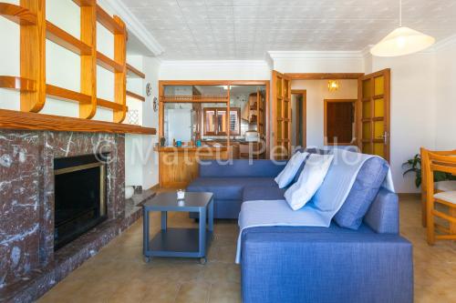 a living room with a blue couch and a fireplace at Orellana in Can Picafort