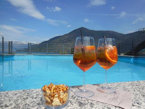 two wine glasses sitting on a table next to a pool at Hotel Giardino in Cannobio