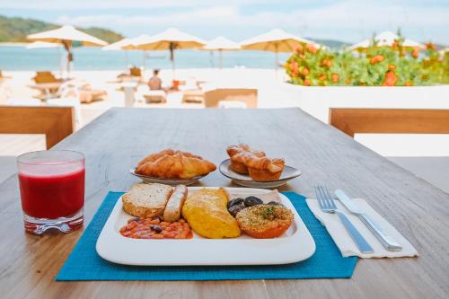 a table with a plate of food and a glass of juice at Dash Resort Langkawi in Pantai Cenang