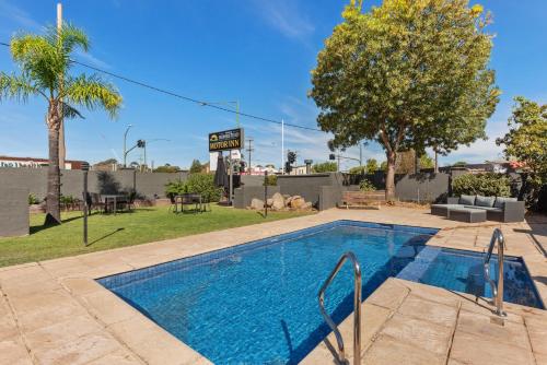 a swimming pool in a yard with a park at Homestead Motor Inn & Apartments in Bendigo