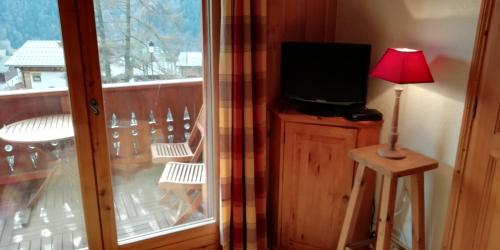 une télévision assise sur un support à côté d'une fenêtre dans l'établissement Le Lièvre Blanc, appartement N°2, aux Contamines-Montjoie