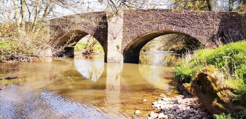 an old stone bridge over a river at Kingsley Cottage in Beaworthy