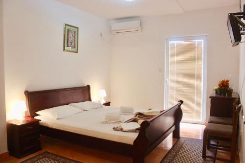 a bedroom with a bed with white sheets and a window at Nir Apartments Budva in Budva