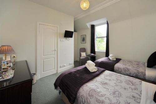 a hotel room with two beds and a window at Dunallan Guest House in Grantown on Spey