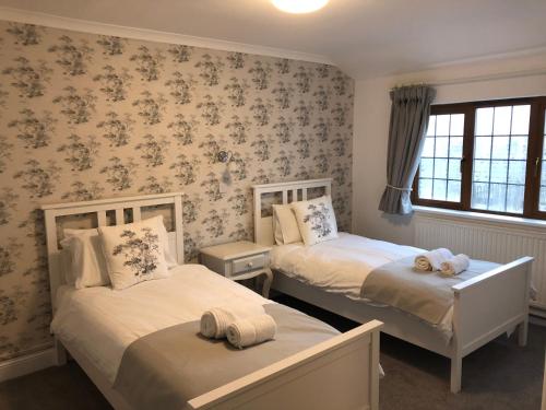 two beds in a bedroom with floral wallpaper at Raleghs Cross Inn in Watchet