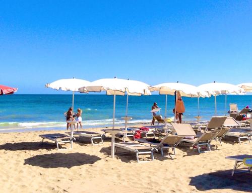 a group of people on a beach with chairs and umbrellas at Villa Le Palme in Rosa Marina