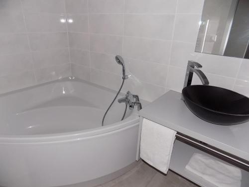 a bathroom with a tub and a black bowl on a counter at Logis Hôtel Le Régal & Spa in Saint Die