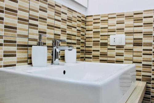a white sink in a bathroom with brown tiles at Le Amiche in Marina di Ragusa
