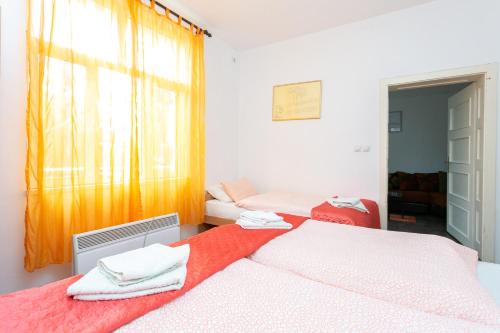 a bedroom with two beds and a window with orange curtains at Apartments Ozren in Soko Banja