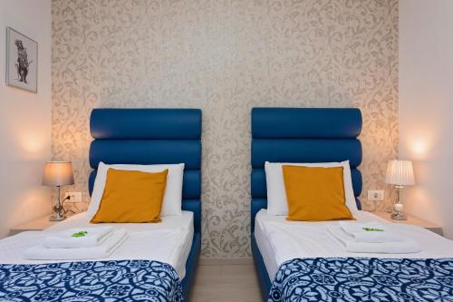 two beds in a room with blue and yellow pillows at S. Martino Rooms in Pula