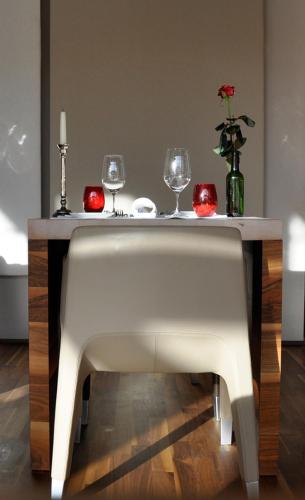 a table with two wine glasses and a vase with a flower at Feldmilla Design Hotel - Wellness & SPA in Campo Tures