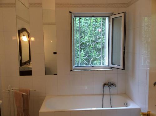 y baño con bañera y ventana. en Villa Le Palme, en Rosa Marina