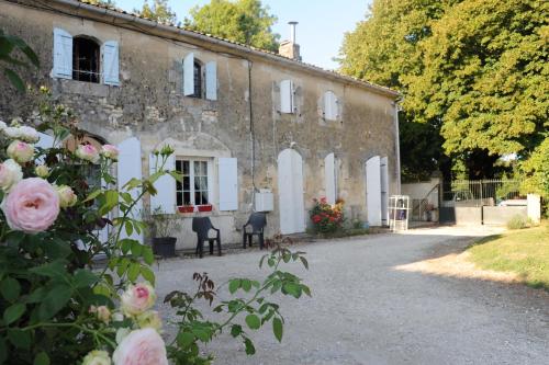 an old stone building with flowers in front of it at Gîte Rouge Calme et Nature in Allas-Bocage