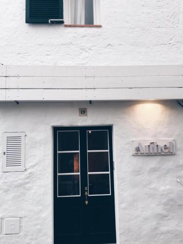 a white building with a green door and a window at HOTEL ANHEL in Ferreries