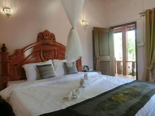 a bedroom with a large white bed with two wedding rings on it at Greenhouse Retreat in Senmonorom