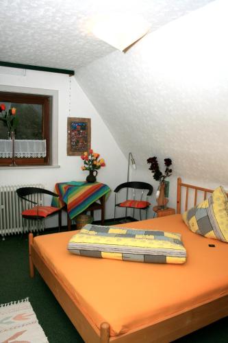 a bedroom with an orange bed with chairs and a table at Frauenpension Arleta - Women only in Goslar