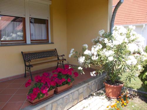 a porch with a bench and flowers in pots at Anna villa in Lenti