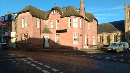 a large brick building with a car parked in front of it at CASTLEBANK HOUSE FLATS, DINGWALL in Dingwall