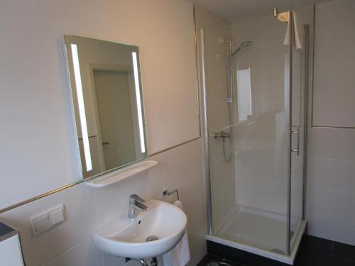 a bathroom with a sink and a shower with a mirror at Schicke Komfortwohnung zum Wohlfühlen in Merchweiler