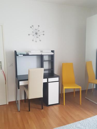 biurko z 2 krzesłami i monitorem komputerowym w obiekcie Homestay Dodo w mieście Lugano