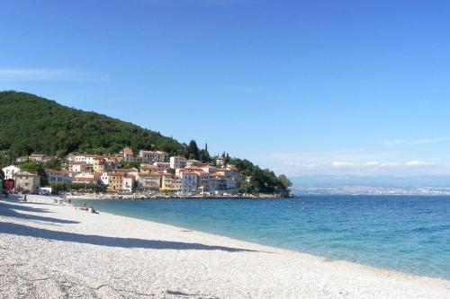 a beach with a town on a hill next to the water at Apartman Peršić in Mošćenička Draga