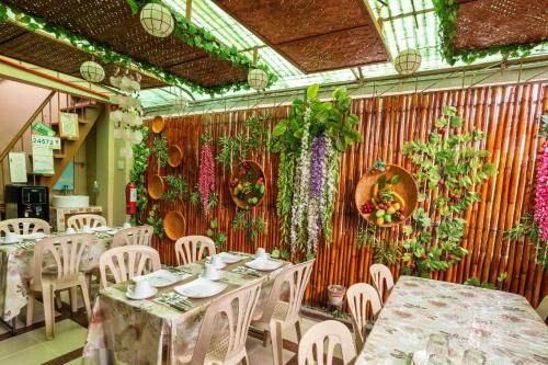 un restaurante con mesas, sillas y flores en la pared en Conrado's Apartelle, en Manila