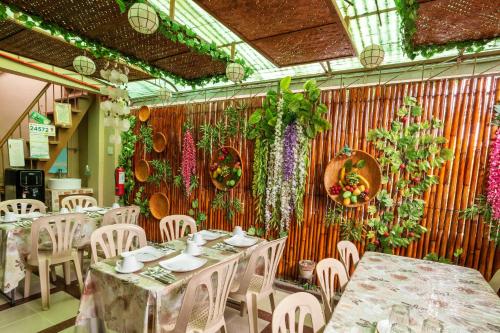 um restaurante com mesas e cadeiras e flores na parede em Conrado's Apartelle em Manila