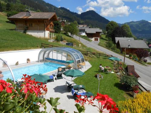 a swimming pool with umbrellas and a resort at Le Chabi in La Chapelle-dʼAbondance
