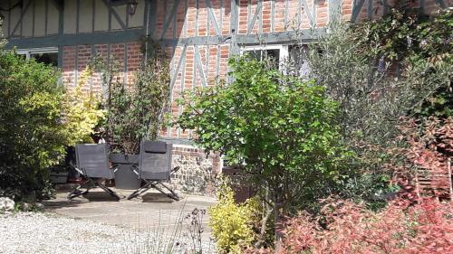 two chairs sitting in front of a brick building at L'Escapade in Foulbec