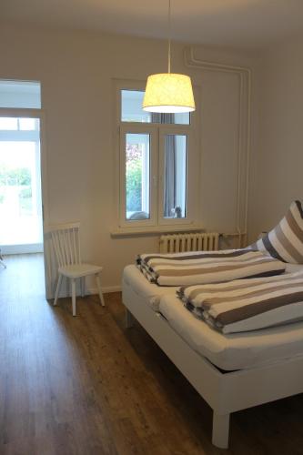 a bedroom with two beds and a chair and a chandelier at Villa Waldheim - WG 3 in Boltenhagen