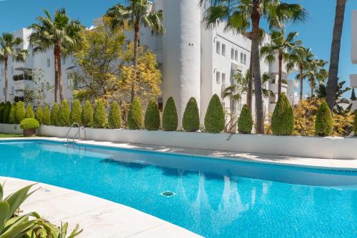 una piscina con palmeras y un edificio en Marbella Real 421, en Marbella