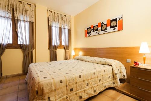a hotel room with a bed and two windows at Vacaciones Tossa de Mar in Tossa de Mar