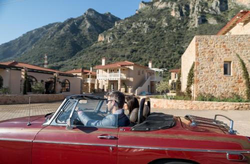 a man driving a red car with a mountain in the background at Kyniska Palace Conference & Spa in Mystras