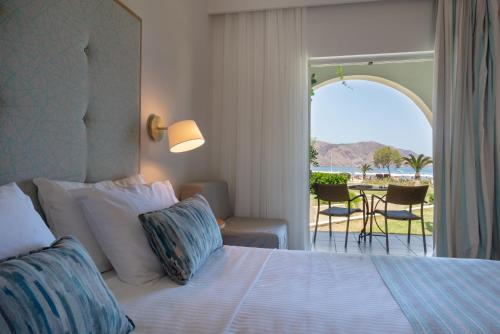 a bedroom with a bed with a view of the ocean at Pilot Beach Resort in Georgioupolis