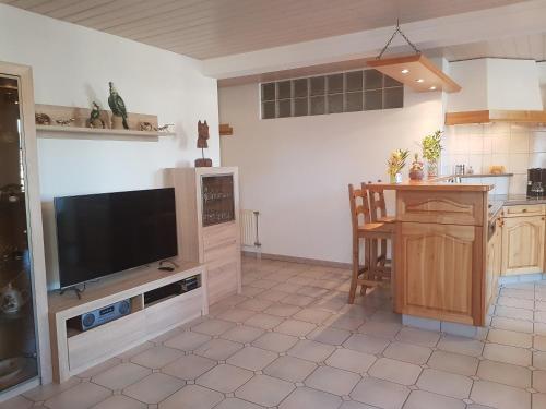 cocina con TV de pantalla plana y mesa en Apartement-Gîte rural à 3 km de Delémont, en Courcelon