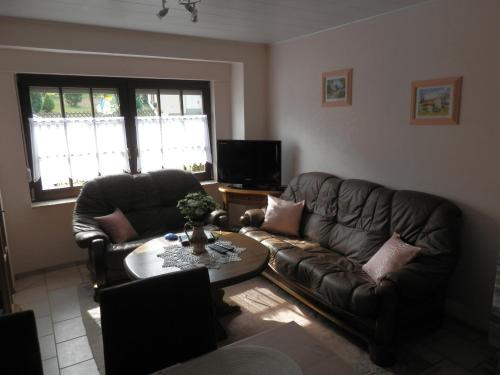 uma sala de estar com dois sofás de couro e uma mesa em Ferienhaus Greta em Malborn