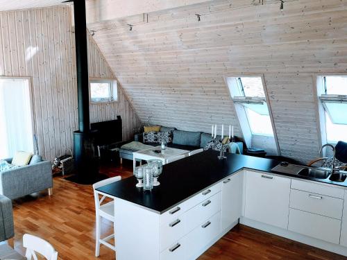 a kitchen with white cabinets and a living room at Kuvågen 23 in Vågenes