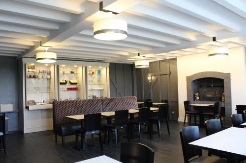 Un comedor con mesas y sillas y una chimenea. en Logis Hôtel Restaurant Le Quai Fleuri, en Voves