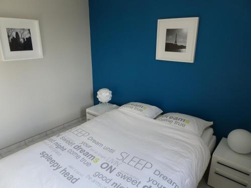 um quarto com uma cama com uma parede azul em Appartement Duinenzicht De Haan-Vosseslag em De Haan