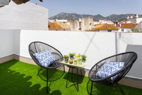 2 sedie e un tavolo sul balcone con erba verde di Genteel Home Tetuan Marbella a Marbella