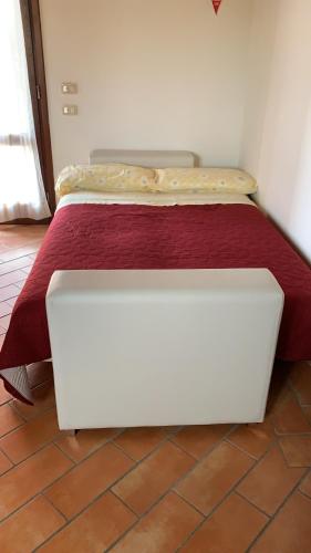 a white bed with a red blanket on top of it at Agriturismo Mimosa in Rispescia